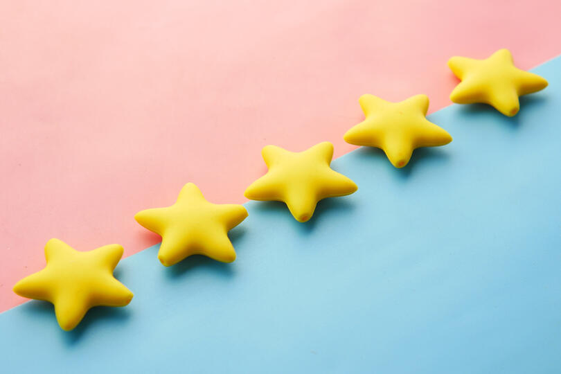 Five yellow stars placed diagonally across a pink and blue background